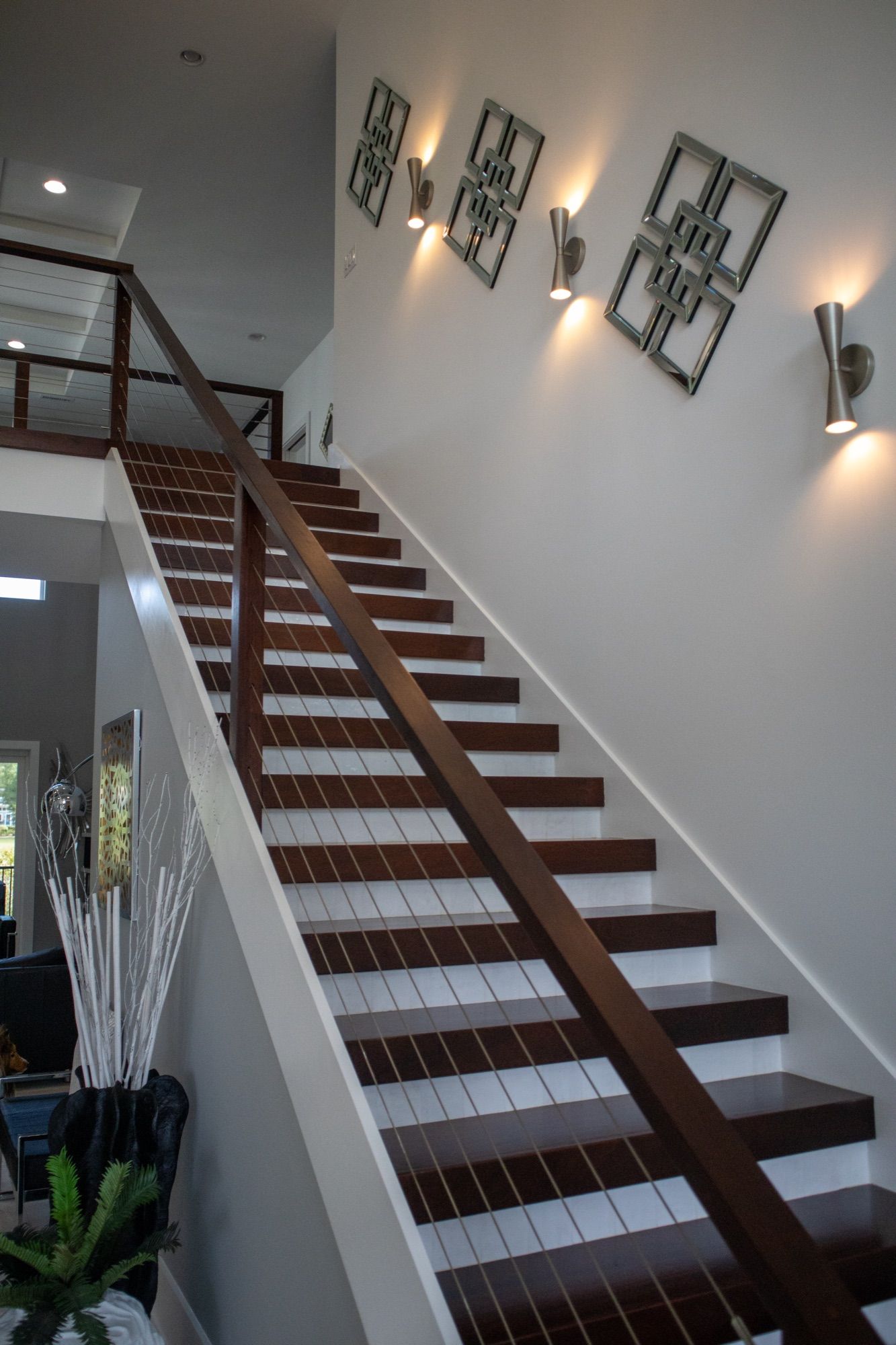 A floating hardwood staircase with a steel cable rail in a Lackey Luxury home.