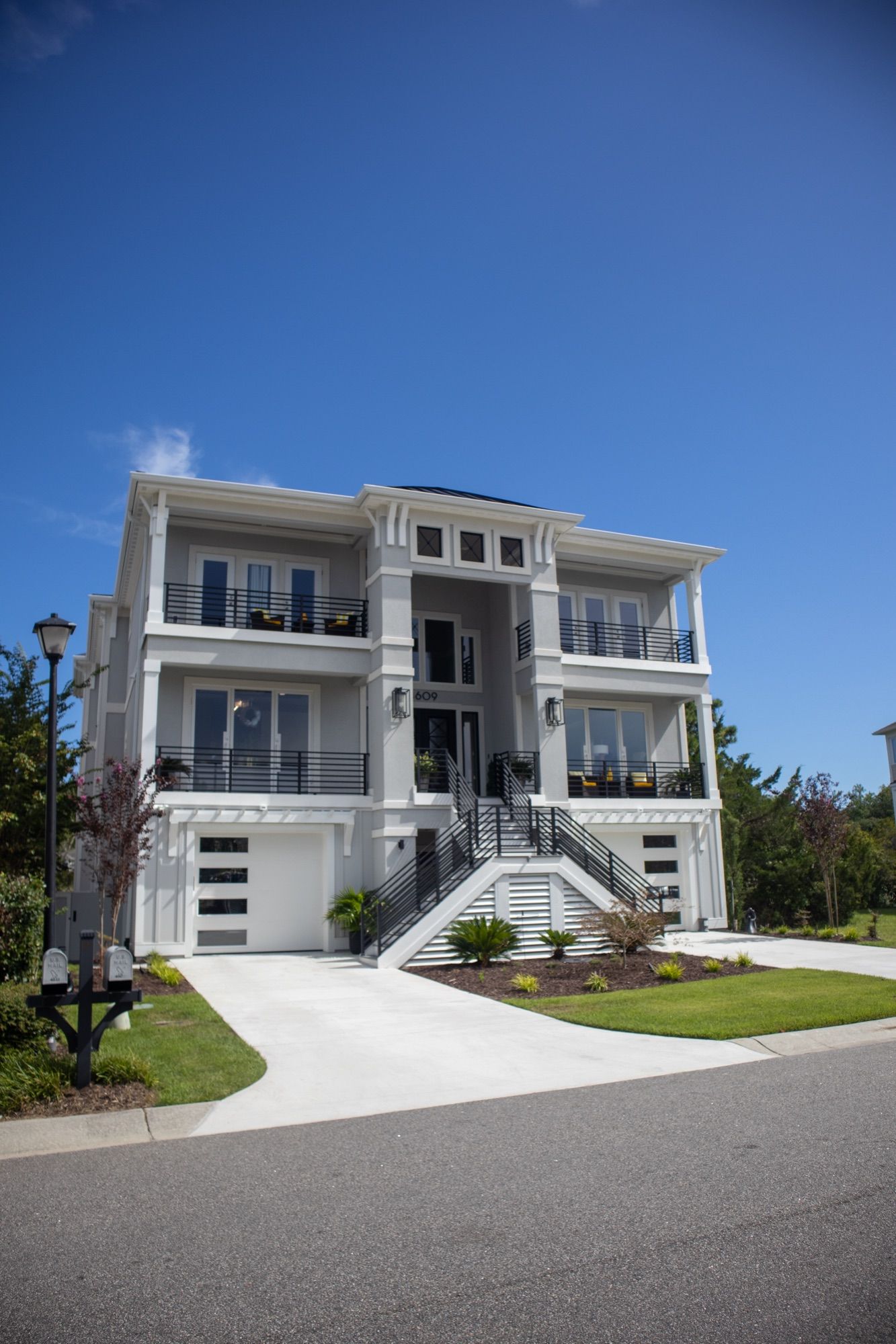 A finished three-story coastal home with wide covered balconies, seen from the street.