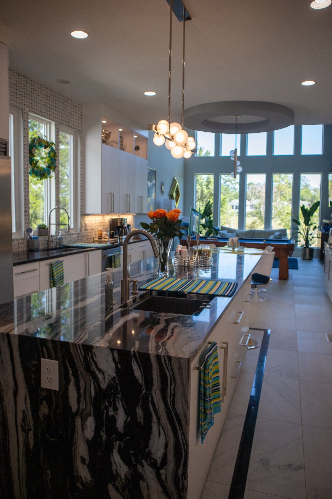 A kitchen with a dark waterfall-edge stone island and bar seating.