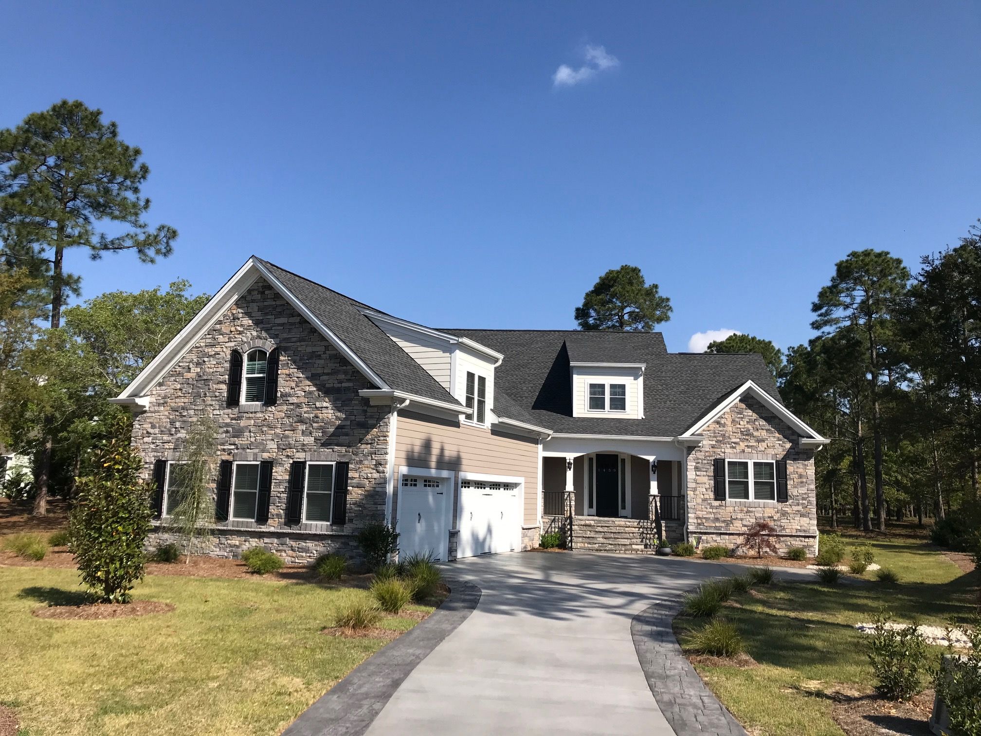 Stacked stone across the front, an arched gable window and a side-entry garage, on a fully landscaped lot.